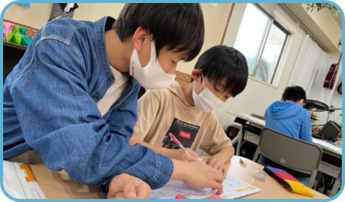 机に向かい、そばでサポートを受けながら学習する様子