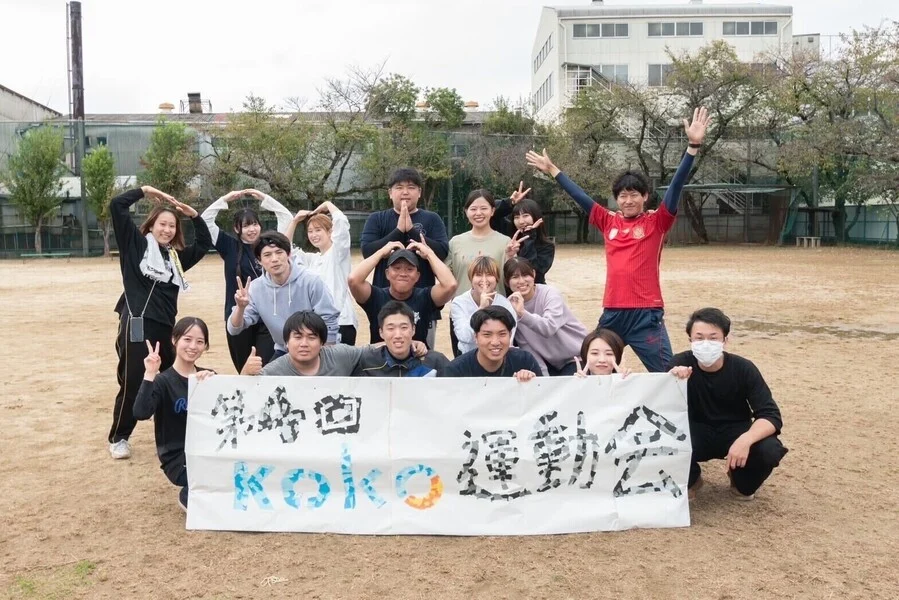 運動会の横断幕を囲む子どもサポーターと職員の交流会の集合写真